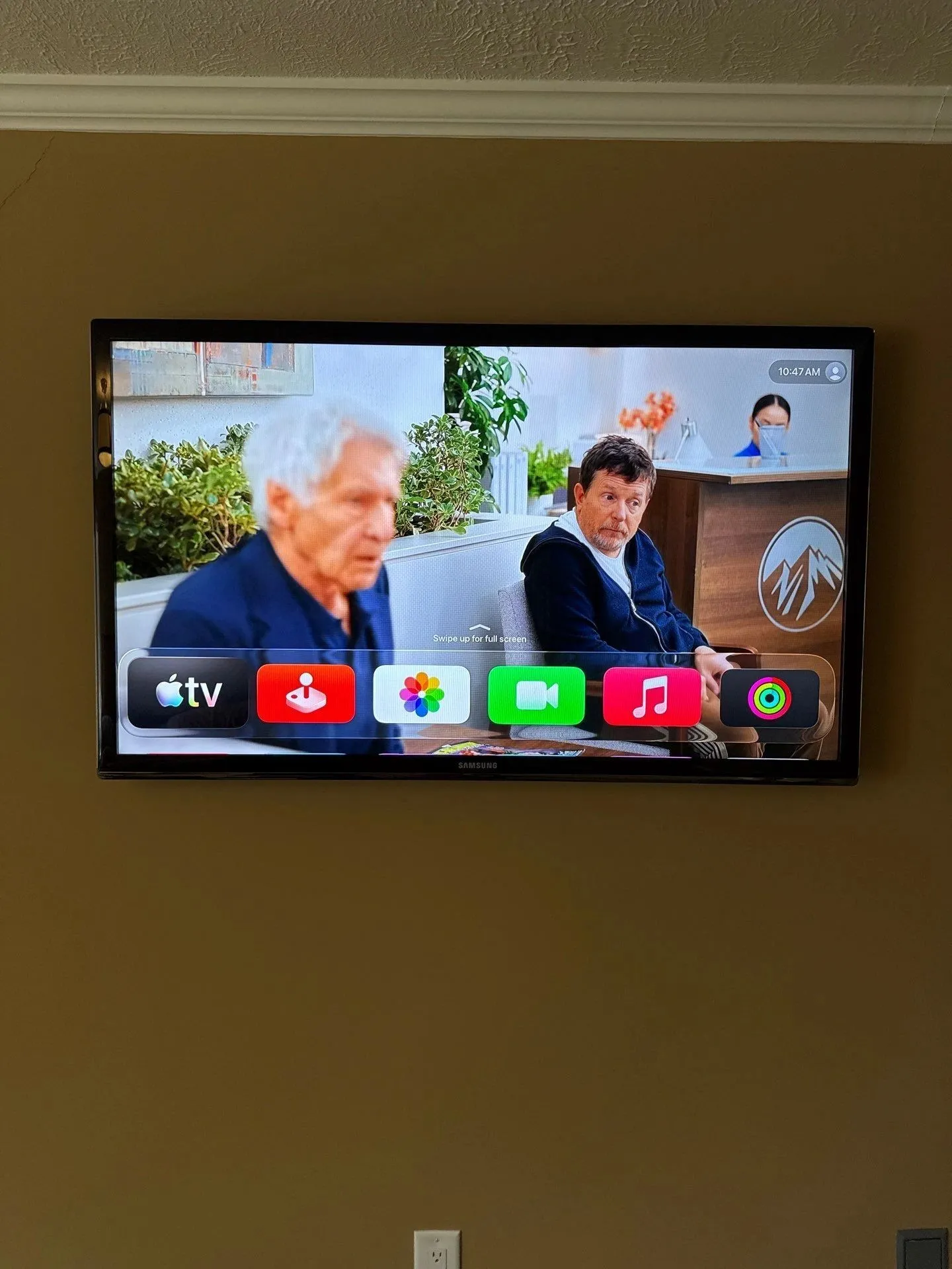 Bedroom TV on a yellow wall showing the Apple TV home screen
