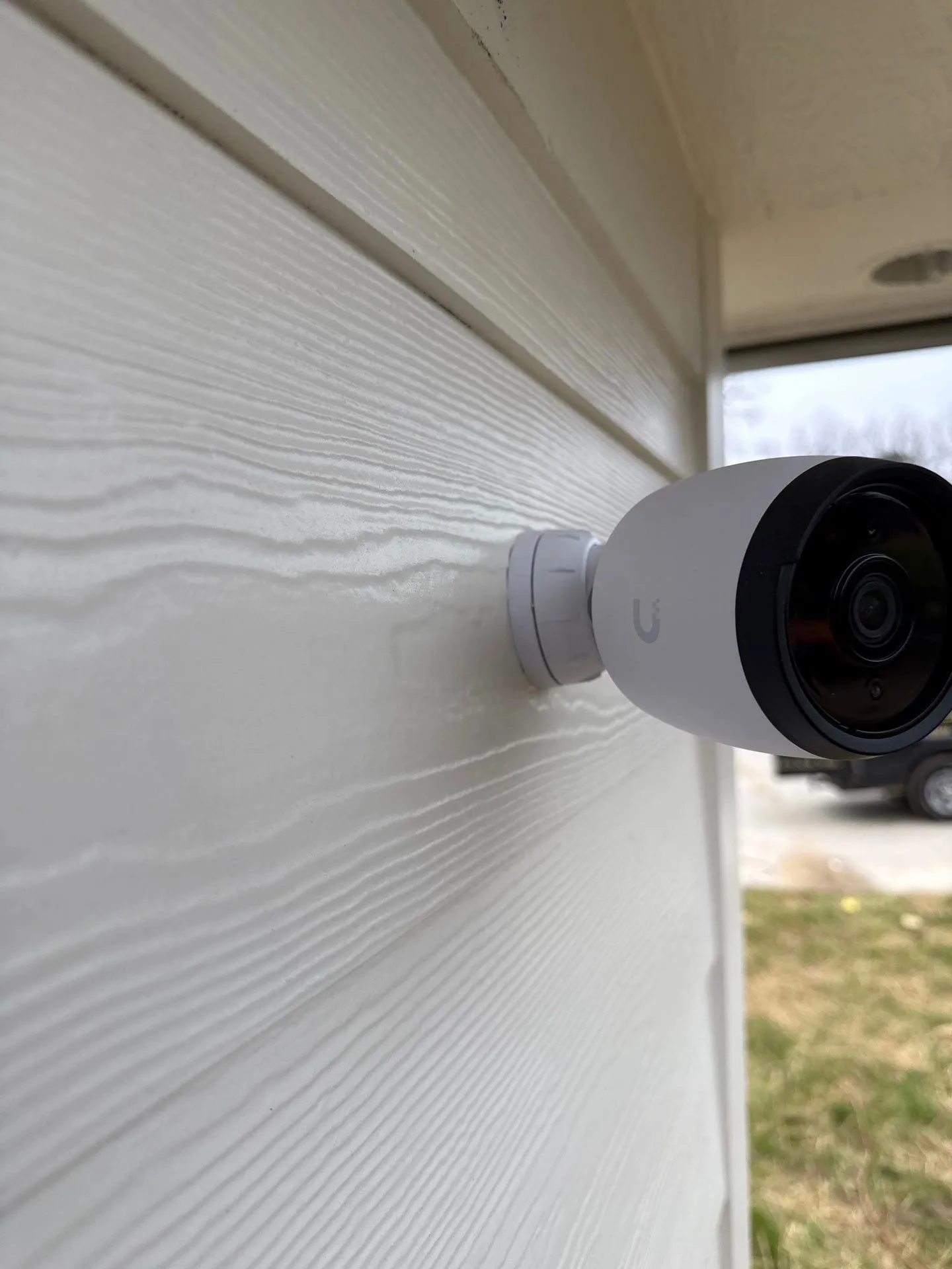 White security camera mounted on lap siding at the corner of a house