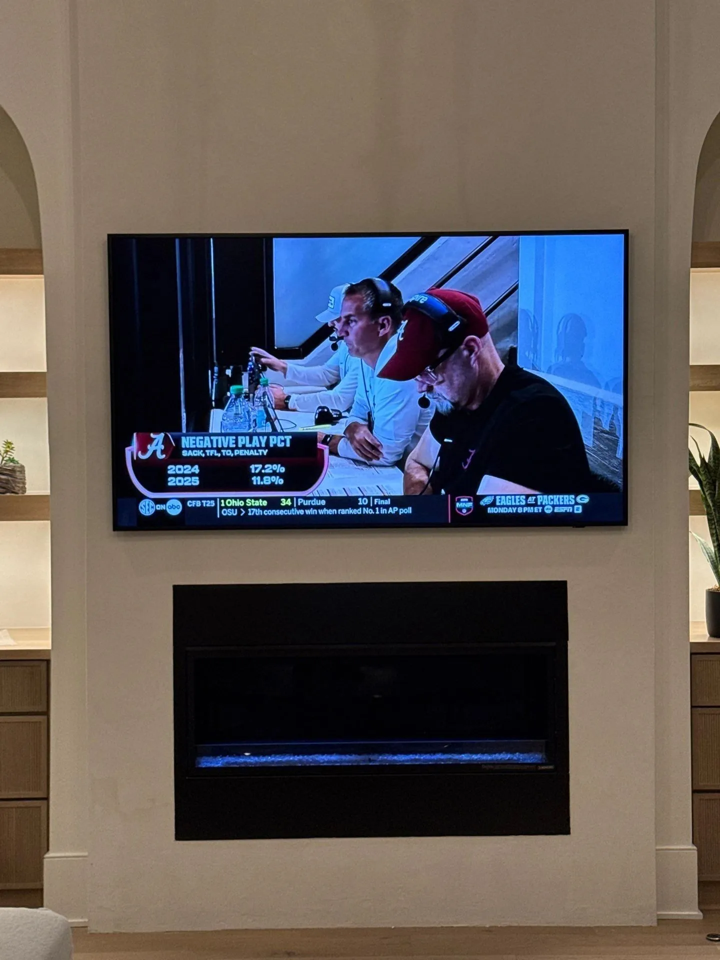 TV over a linear fireplace between built-in shelves in a white living room
